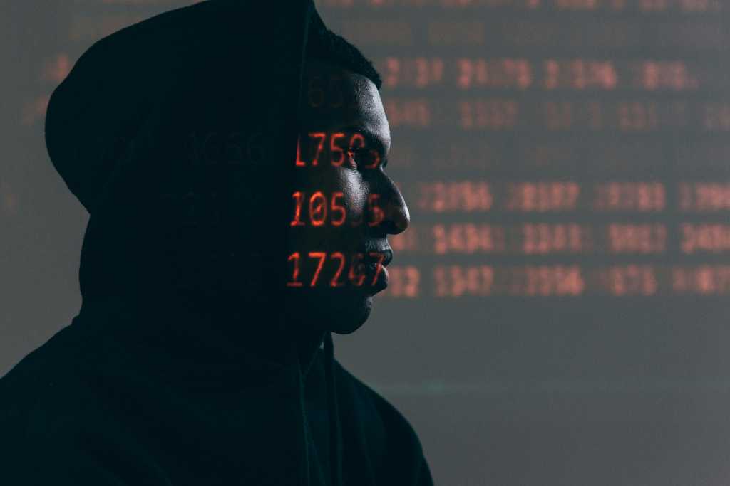 Hacker in a dark room with LED numbers lit on their skin