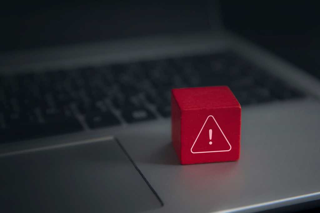 Red warning cube on a laptop keyboard in darkened room